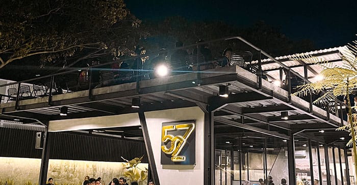 Tampilan malam hari 527 Café Serang dengan logo emas ikonik di fasad bangunan dua lantai, menjadi spot nongkrong outdoor pilihan Dream Home Specialist The Hana Park.