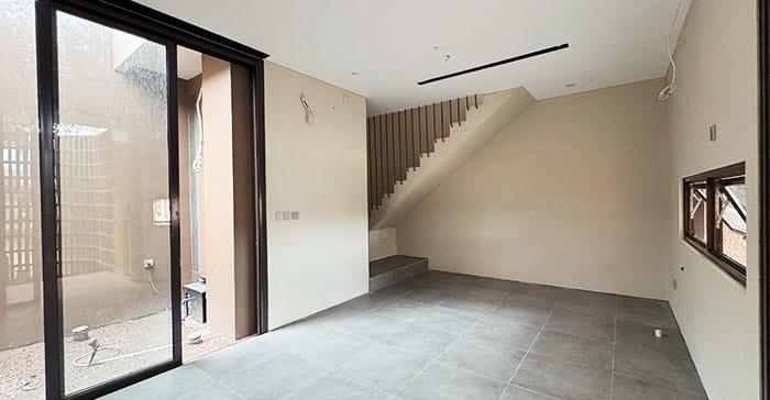 Ruang keluarga rumah The Hana Park dengan pencahayaan alami, bukaan kaca besar, dan desain minimalis modern