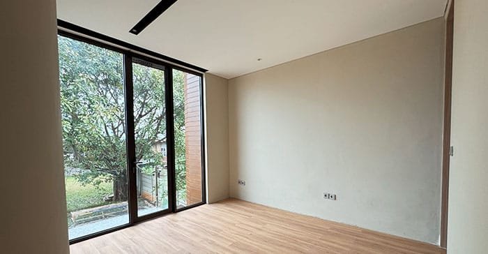 Kamar tidur hunian The Hana Park dengan jendela besar menghadap taman dan pencahayaan alami maksimal
