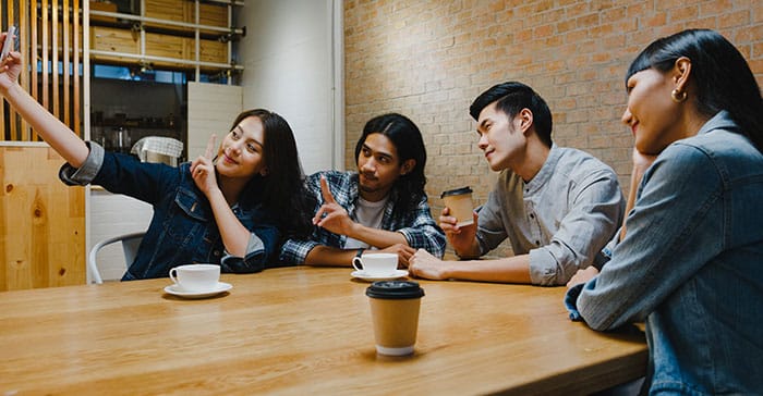 Empat anak muda sedang hangout sambil ngopi dan selfie di dalam cafe, mencerminkan suasana akrab dan nyaman seperti yang ditawarkan 527 Café Serang dan gaya hidup di sekitar The Hana Park.