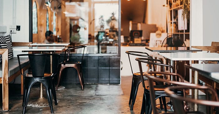 Interior Kopi Rona Serang dengan nuansa hangat dan kursi besi industrial, tempat favorit Dream Home Specialist The Hana Park untuk rehat sejenak dan menemukan inspirasi suasana rumah ideal.